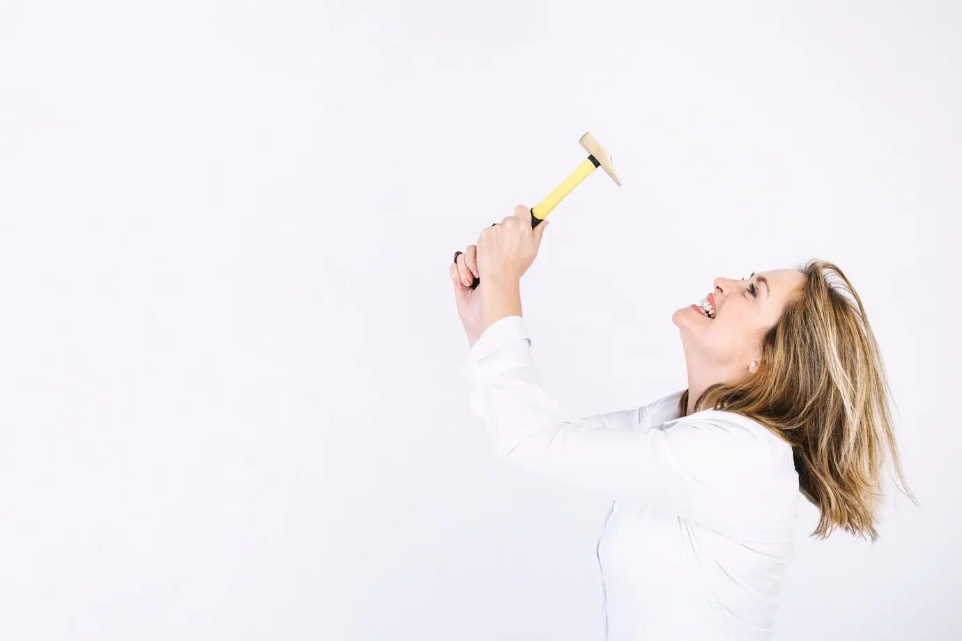 Erwachsene Frau, die mit einem Hammer zu kämpfen hat